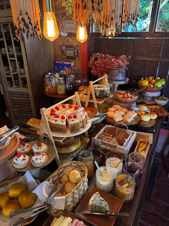 Mesa do café com bolos, pães de queijo, frutas e geleias sob luminárias