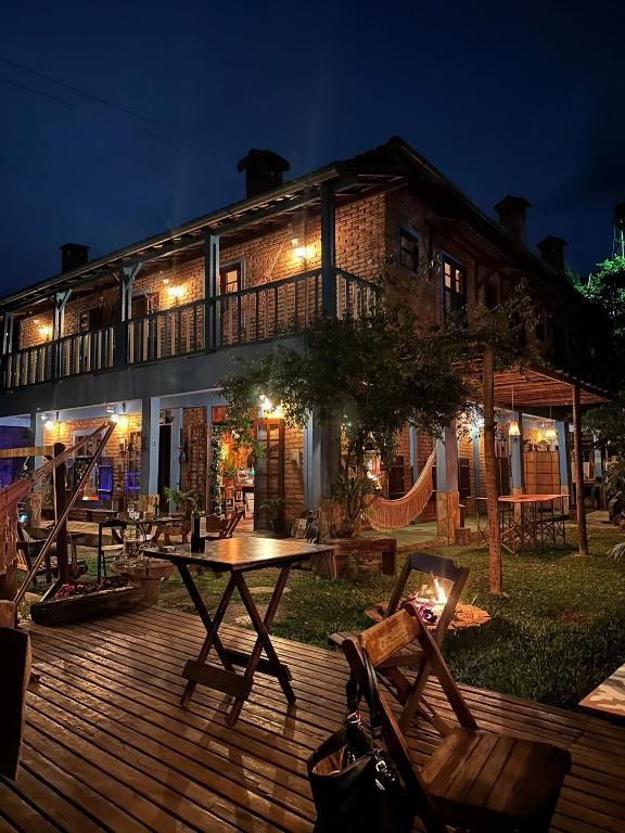 Sobrado de tijolo da pousada iluminado à noite, com deck e jardim
