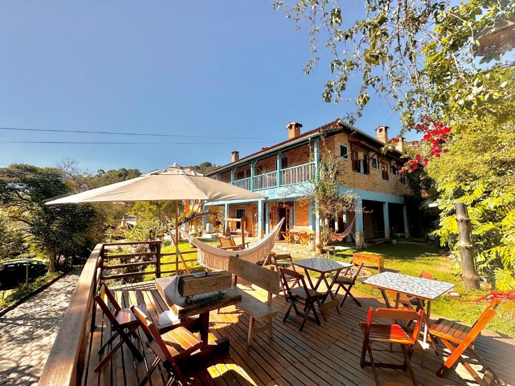 Deck ao sol com guarda-sol, rede e a varanda superior do sobrado ao fundo