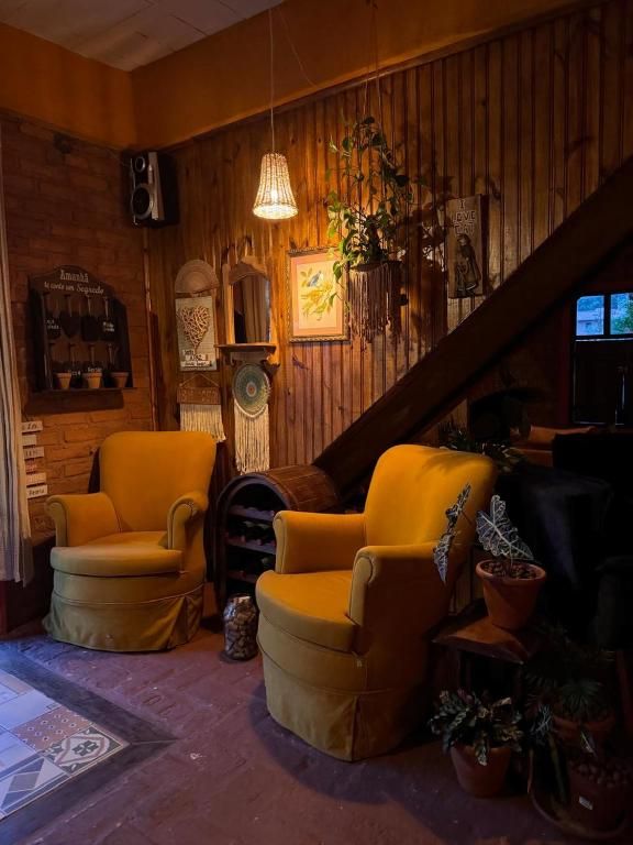 Sala com poltronas amarelas, parede de madeira, plantas e luz baixa