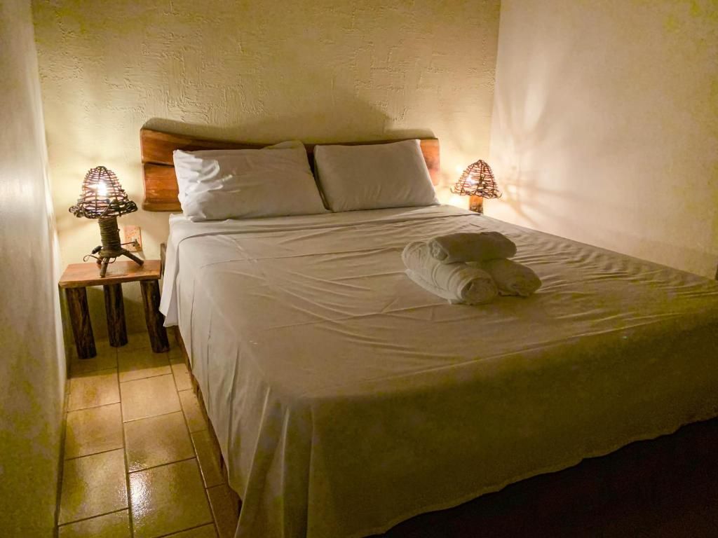 Cama de casal com cabeceira de madeira e abajures de vime